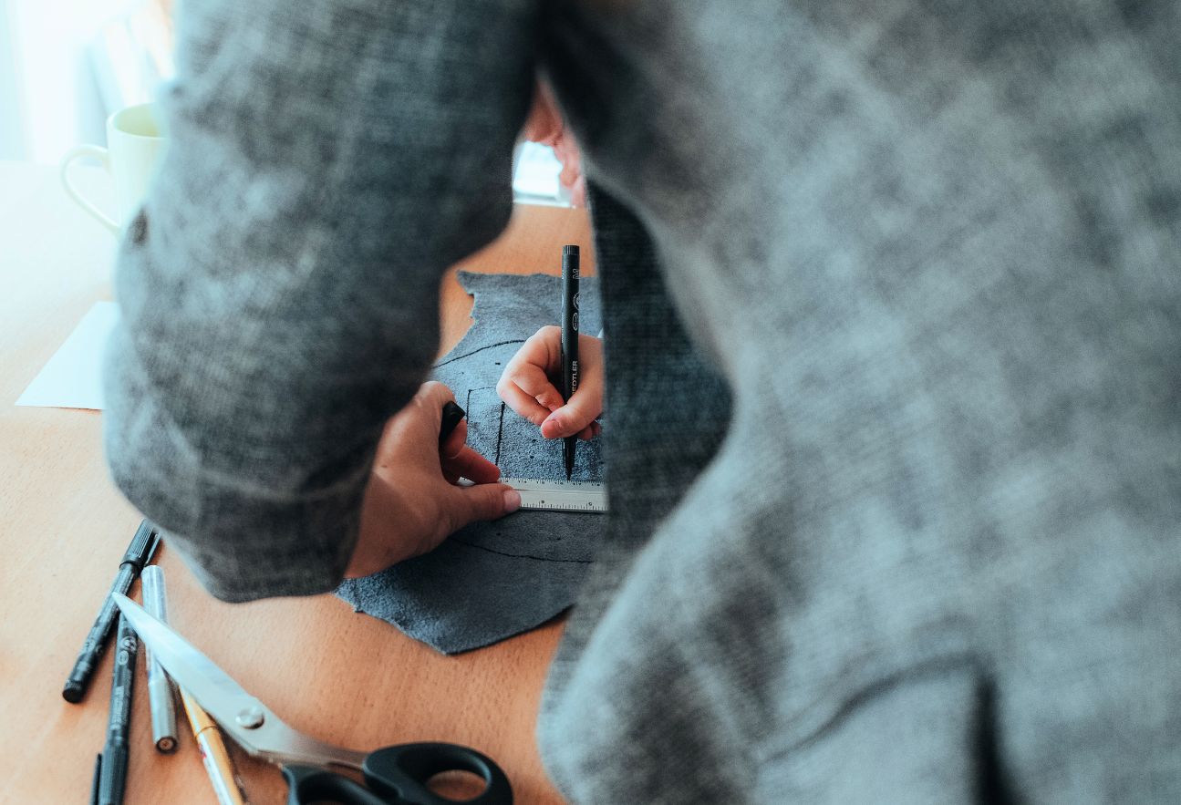 Jemand zeichnet mit einem Stich auf ein Stück Leder beim Basteln