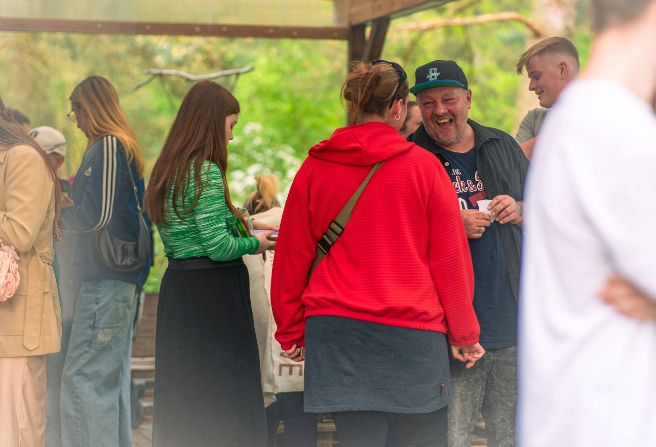 Mehrere Menschen stehen im freien, unterhalten sich und lachen