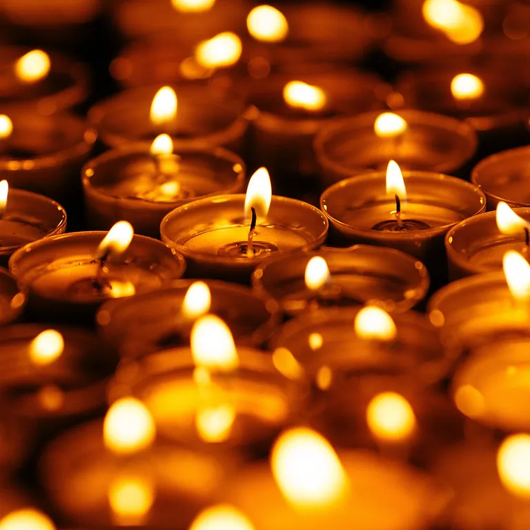 Menschen stehen in einer Kirche vor dem Altar; einige tragen weiße Chorumhänge, im Vordergrund und auf den Bänken ist die Gemeinde zu sehen.
