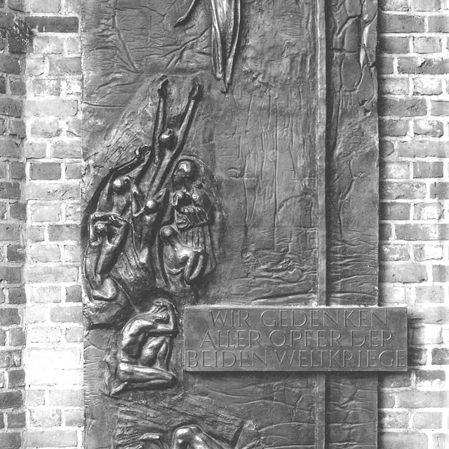 Bronzerelief der Ehrentafel von Heinz Spilker (1964) zum Gedenken an die Opfer beider Weltkriege an der Klinkerwand neben dem Eingang