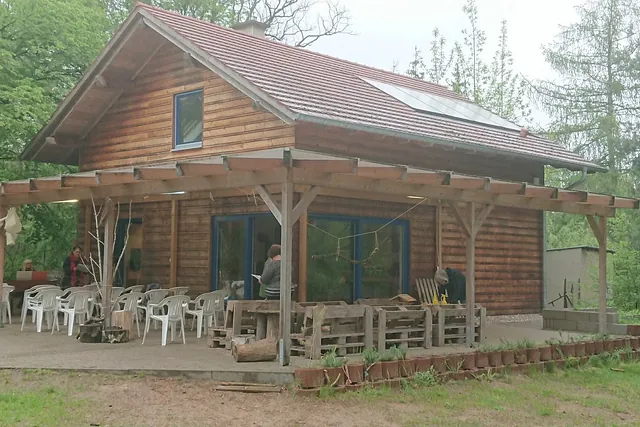 Holzhaus mit überdachter Veranda, Gartenstühlen und Tischen auf der Terrasse