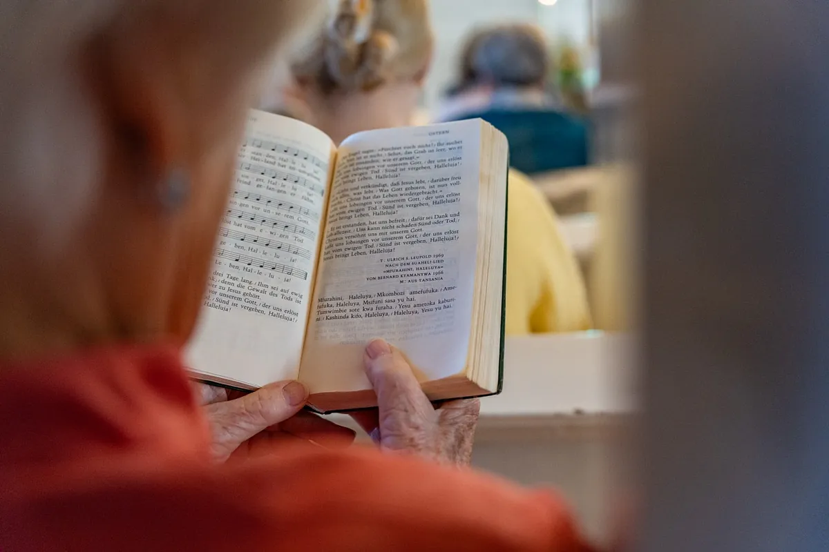 Ein Frau hält ein Gesangbuch in der Hand