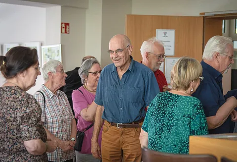 Mehrere Senior:innen stehen zusammen und unterhalten sich lachend