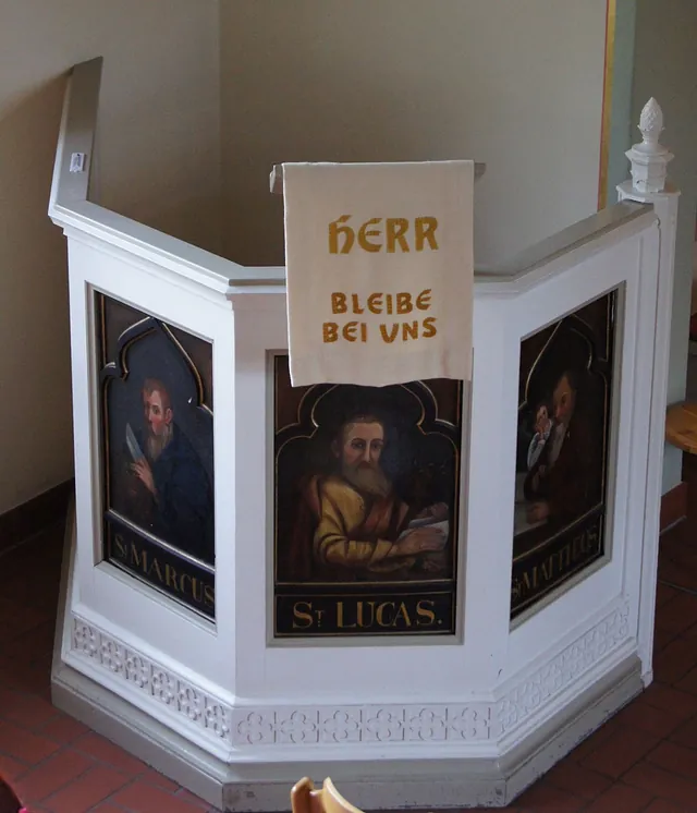 Weiße Kanzel von 1839 aus der Spandauer Nikolaikirche mit gemalten Evangelistenbildern und dem Behang „Herr bleibe bei uns“