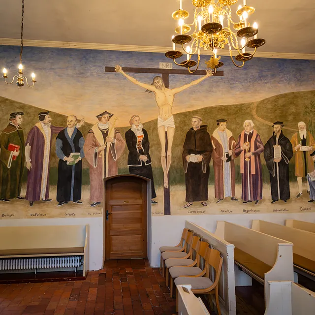 Innenraum der Dorfkirche mit dem Wandbild „Versöhnte Einheit“, Kronleuchter und Kirchenbänken
