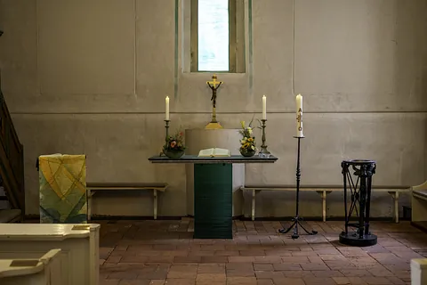Altar der Dorfkirche Alt-Staaken mit brennenden Kerzen, Kruzifix und Osterkerze