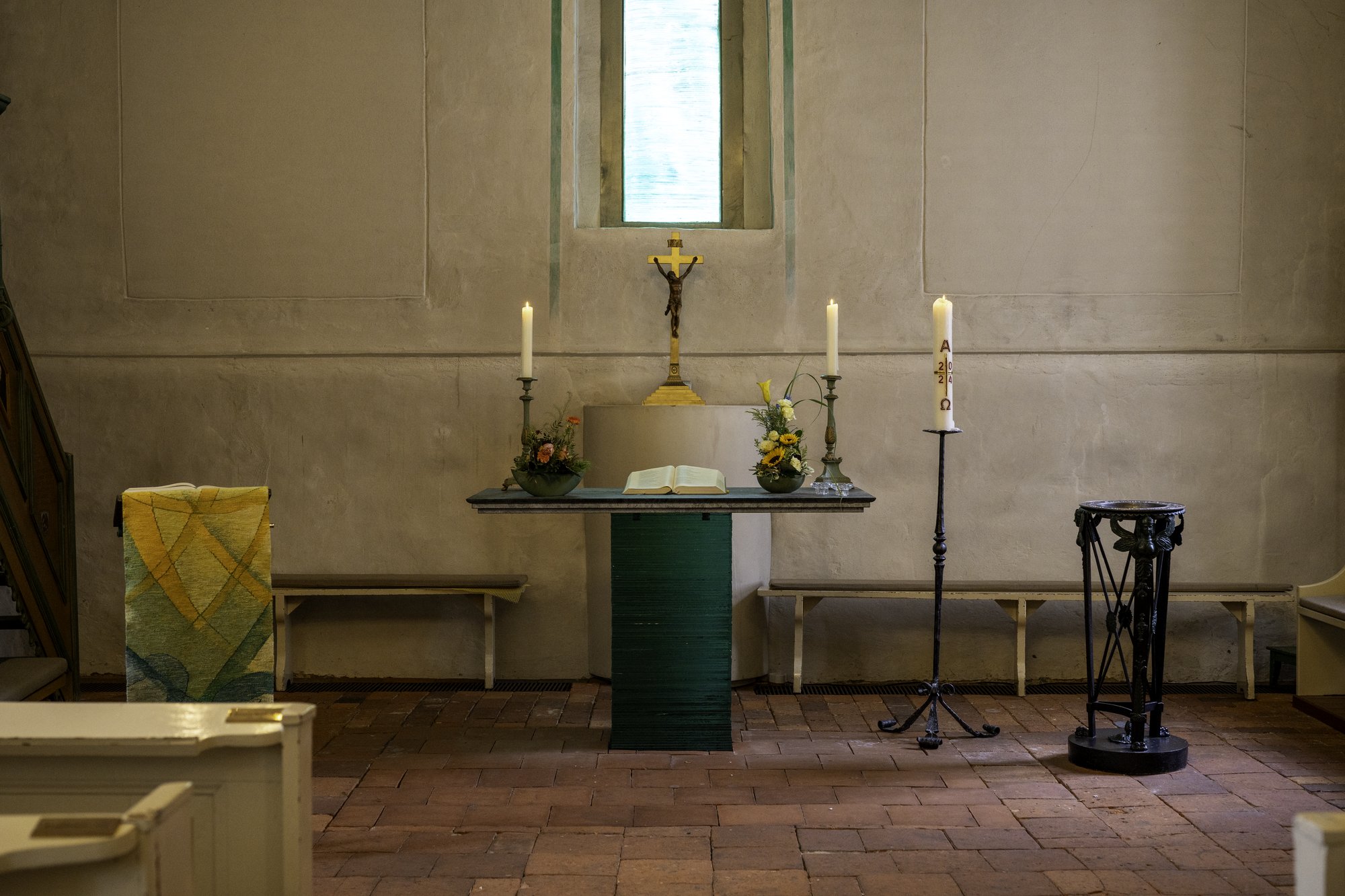 Altar der Dorfkirche Alt-Staaken mit brennenden Kerzen, Kruzifix und Osterkerze